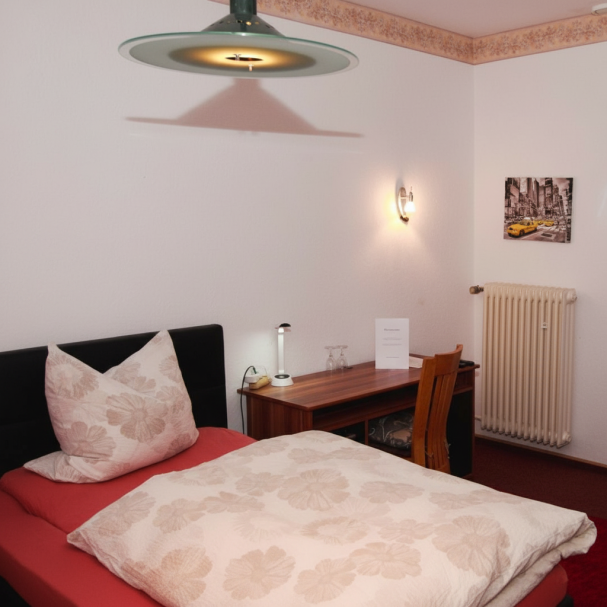 Schlafzimmer mit einem Bett, Schreibtisch und einem wandmontierten Heizkörper.